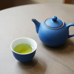 photograph of a blue teapot on a table next to a cup of green matcha tea, portra 800