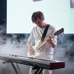 white dusty Trent Reznor smashing a guitar on a synthesizer, dust, smoke, giant LED screens, colored projections, ultrafine detail, cybersuit, glowing thing wires, smoke, high contrast, projections, associated press photo, masterpiece