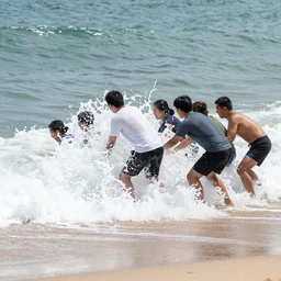 A group of people trying their best to hold back and stop waves from crashing into the beach