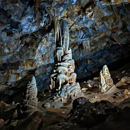 professional photograph of the inside of a dark cave, rocky interior, stalactites and stalagmites, wide view