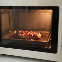 Steak being cooking in a microwave, viewed through the closed microwave window, cursed