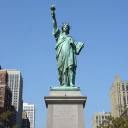 the green copper statue of katniss everdeen stands atop a large plinth with new york below
