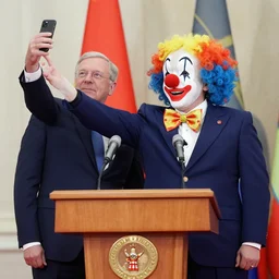 president with clown head taking a selfie in a podium next to first minister
