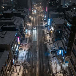 a city street at night, snowing, photograph, cyberpunk, sharp focus, intricate detail, Desolate, drone shot, high resolution, 8k, neon streetlights, wires hanging down everywhere