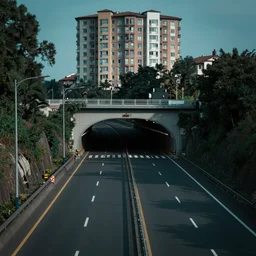 establishing shot of a large highway, an apartment building directly above the large highway, tunnel entrance, wide establishing shot, dark teal lighting, soft dramatic lighting, sharp focus, 4 k digital camera