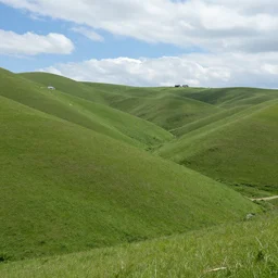 empty green grassy hills with blue cloudy sky with isolated houses scattered unnaturally across the steep hills