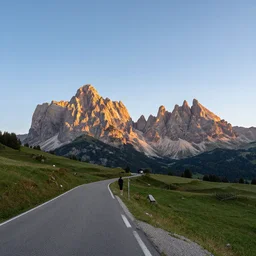 the most beautiful photo landscape of the dolomites, there is a road and next to it a person is watching the sunset at the border of a cliff, the sky has a wonderful lenticular cloud, the photo was taken by max rive, golden hour, super resolution, masterpiece, international photography awards winner