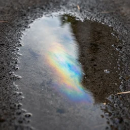 close - up of a puddle of fuel, gas, diesel, iridescent shine reflection