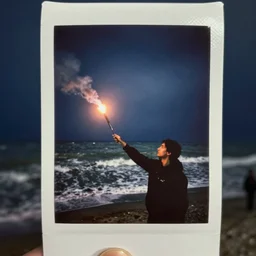 lomo photo of a man holding a flare in a stormy sea, cinestill, bokeh, out of focus, night, dramatic lighting, streetlight