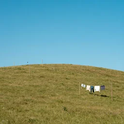 photo of a hilly field with randomly-placed clotheslines, surreal, blue sky