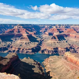 color still of the grand canyon filled with blue water, sunny, blue fluffy clouds,