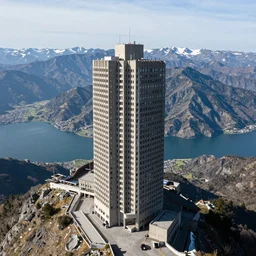 photograph of a massive brutalist building on top of the highest mountain, landscape with lakes and snowy mountains,