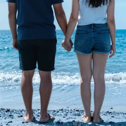 couple holding hands standing on a blue beach