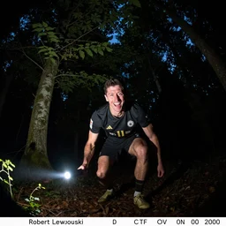 laughing robert lewandowski creeping towards the camera on trail cam at night, in a dark forest, lit by a flashlight, fisheye!!!