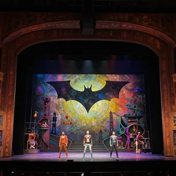 photo of a huge theaterstage, play is dark knight, 3 actors on stage, 8 k, multicolored, exaggerated detailed, long shot