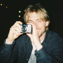a disposable camera picture of kurt cobain smiling while trying to grab the camera, out of focus, bokeh, 1 9 8 5