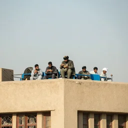 Taliban member eating subway on top of a building