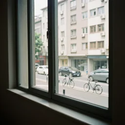seeing my reflection in the window as I look out to another building and bicycles and cars