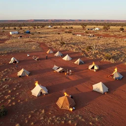 aerial shot of a burningman themed campsite, in the australian red desert with dry grass