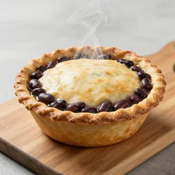 bokeh photograph of a black bean pie steaming on a wooden cutting board
