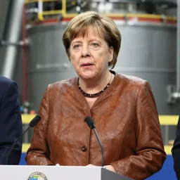 Angela Merkel wearing a tailored brown leather jacket at a press conference in a nuclear reactor