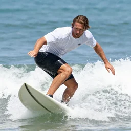 a closeup photorealistic photograph of wayne gretzky riding a surf board while operating a film camera. bright scene. fine detail. this 4 k hd image is trending on artstation, featured on behance, well - rendered, extra crisp, features intricate detail, epic composition and the style of unreal engine.