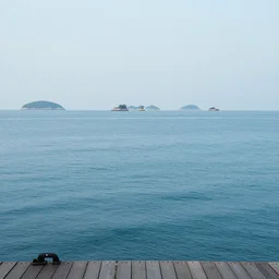 a still ocean with floating islands in the far distance, dock view