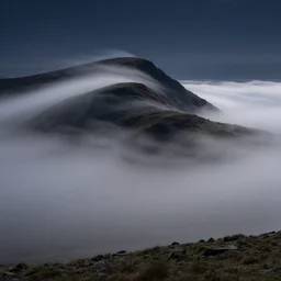 beautiful nocturnal birds eye long exposure view of a stunning welsh hill and landscape sculpted from long fluttering interlaced plumes of mist and fog and wind