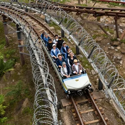 a rollercoaster, tracks of barbed wire, birds eye view, hyperrealistic