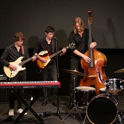 photography of a 4 man band with a keyboard and electric guitar player, a skiny singer that also plays electric guitar a really tall bass player and a black drummer, award winning photography