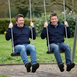 simon Cowell and Steve Bruce having fun on the swings at the park