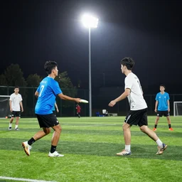 “ a photo of two teams playing ultimate frisbee on a soccer field at night with stadium lights ”