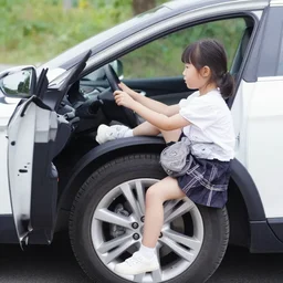 small girl sitting on the wheel in the car and driving
