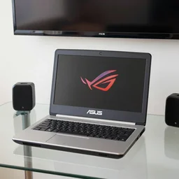 vintage photograph of a ASUS ROG laptop sitting on a glass desk with a tv monitor above it, mini speakers are behind the laptop, a Liptopn Diet Green Tea bottle is beside of the laptop, coffe cup on desk, noir film still
