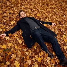 Andrew Tate laying in a pile of autumn leaves