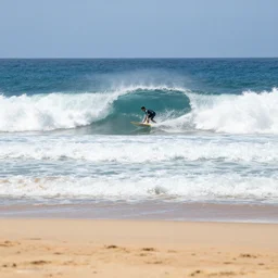 big wave surfing, sandy beach in foreground