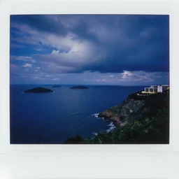micro - hurricane, blue hour, deep blue atmosphere, scattered islands, sea, ocean, royal blue sky, low pressure system, cloud with eye, very windy, late evening, distant hotel retreat on cliffside, polaroid photograph