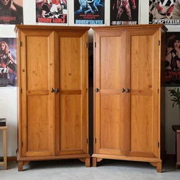 two large armoires with slightly crooked doors in a room full of posters