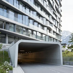 denis villeneuve establishing shot of modern bjarke ingels condo building and gotthard tunnel entrance combined, roads tunnel under bjarke ingels condo building, lush environment, ray traced sunny raked lighting, scifi artstation digital concept art, unreal engine, hyper realism, realistic shading, cinematic composition, blender render, octane render, wide shot