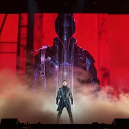 dusty Trent Reznor, elaborate stage effects, dust, smoke, giant red LED screens, colored projections, ultrafine detail, goth cybersuit, glowing thin wires, smoke, high contrast, projections, associated press photo, masterpiece