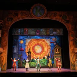 photo of a huge theaterstage, play is the wizard of oz, 3 actors on stage, 8 k, multicolored, exaggerated detailed, long shot