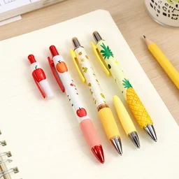 photo of novelty pens designed with the themes of an apple and a pineapple, placed on a writing - desk.