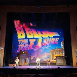 photo of a huge theaterstage, theaterplay is back to the future, 3 actors on stage, 8 k, multicolored, exaggerated detailed, long shot