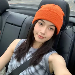 girl lounging in a convertible car wearing an orange beanie and a grey tie-dye sleeveless shirt, selfie, faint smile