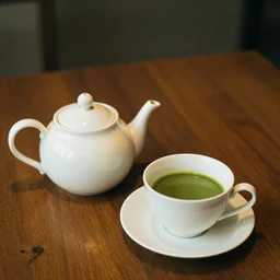impressonism nostalgic photograph of a teapot on a wooden table next to a cup of matcha tea, portra 800