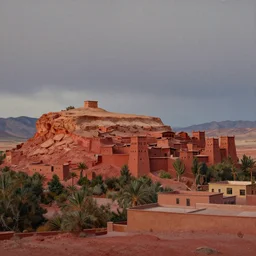 scenic view of a Kasbah town atop a flat topped red hill, in the Nevada desert, overcast dusk, fewer buildings around the hill, matte painting in the style of marc somonetti and james gurney