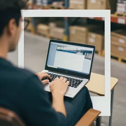 a close up man using a laptop inside in warehouse, he sitting on chair and small table, polaroid photo, view from back