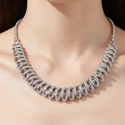 catalog photograph of a woman's necklace in white gold. the necklace sparkles around the model's neck, reflecting and refracting light. the necklace is made up of lots of small gold rings encrusted with precious stones.