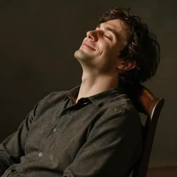 a man is sitting in a chair he has his eyes closed and his head is leaned back there is a smile on his face and he looks content