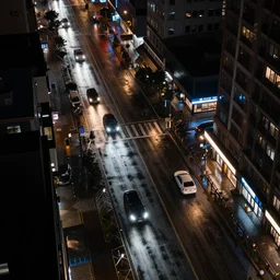 a city street at night, raining, photograph, cars on the road, cyberpunk, sharp focus, intricate detail, drone shot, quick shutter speed